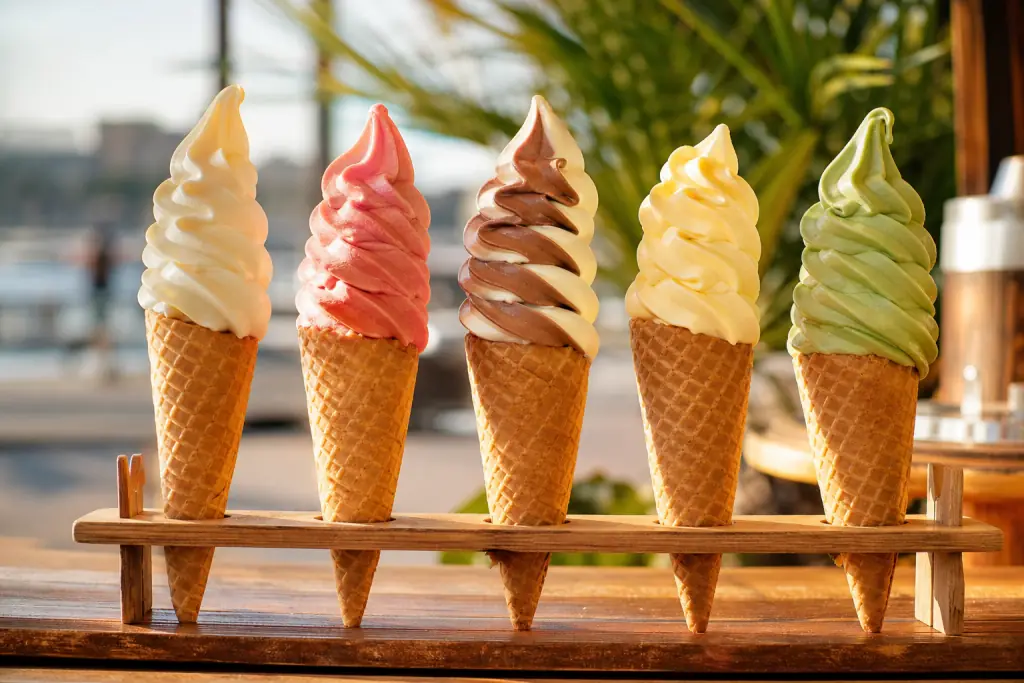 Plusieurs torsades de glace italienne de parfums variés alignées au soleil sur cornets pointus